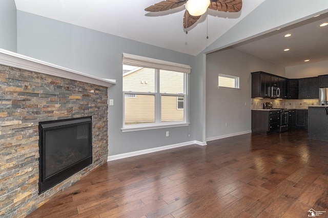 unfurnished living room with ceiling fan, a fireplace, baseboards, vaulted ceiling, and dark wood finished floors