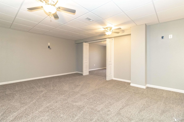 basement with a drop ceiling, visible vents, a ceiling fan, baseboards, and carpet