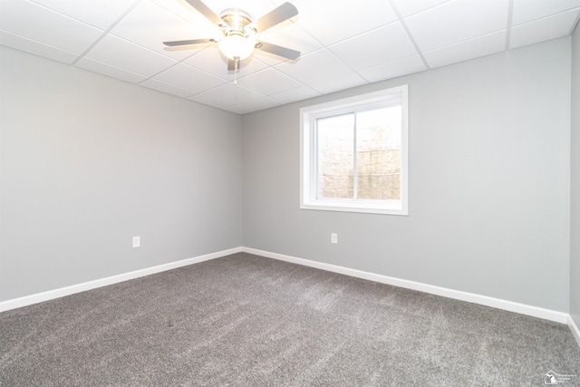 empty room with ceiling fan, carpet floors, a drop ceiling, and baseboards