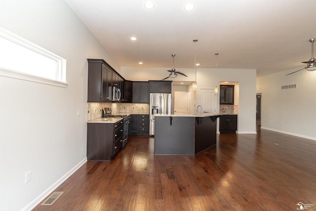 kitchen featuring stainless steel appliances, visible vents, a kitchen bar, and a ceiling fan