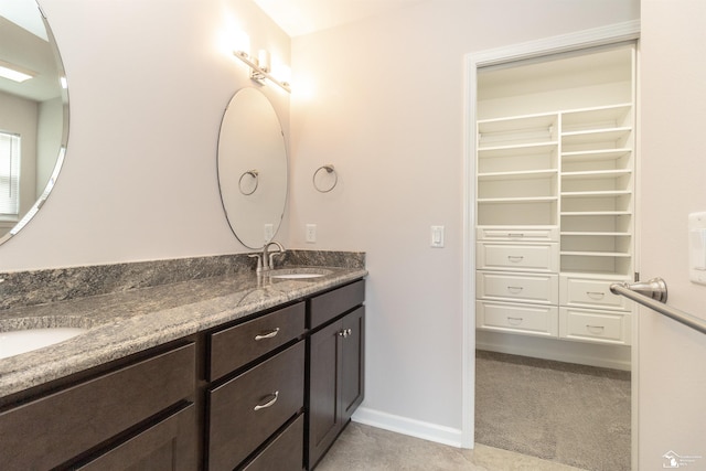 full bathroom featuring a sink, a spacious closet, baseboards, and double vanity