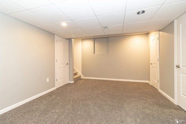 finished basement featuring carpet floors, a paneled ceiling, and baseboards