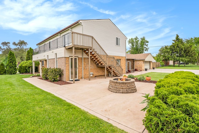 back of property with a garage, a fire pit, stairway, a yard, and brick siding