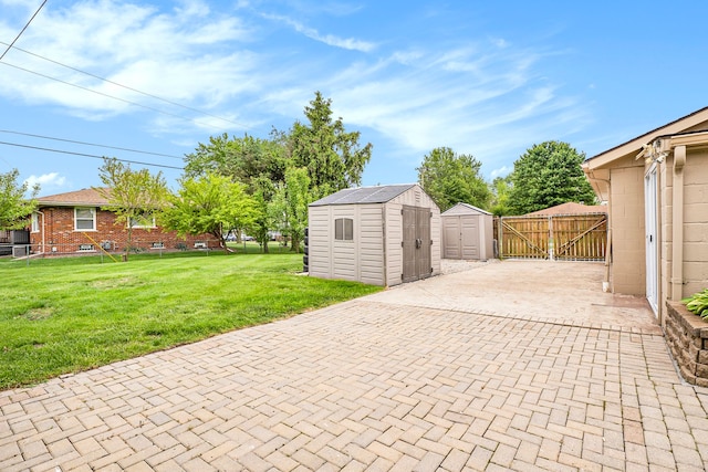 view of patio / terrace with a storage shed, an outdoor structure, fence, decorative driveway, and a gate