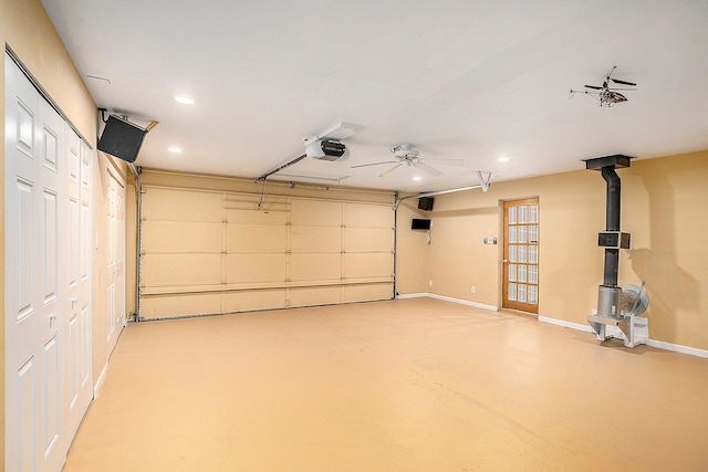 garage featuring a garage door opener, recessed lighting, a wood stove, and baseboards