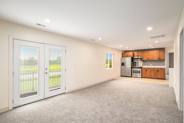 unfurnished living room with french doors, recessed lighting, visible vents, and light colored carpet