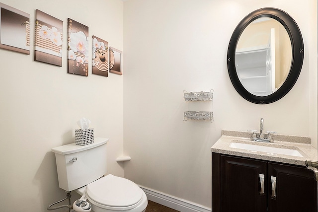 bathroom featuring baseboards, vanity, and toilet