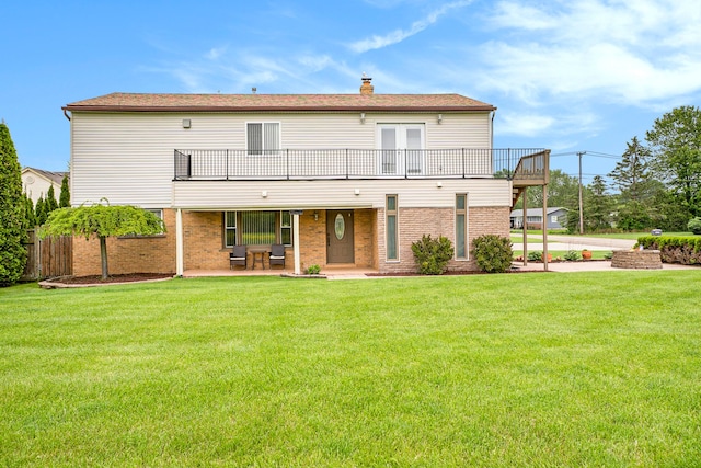 rear view of house featuring a patio, a yard, a chimney, and brick siding