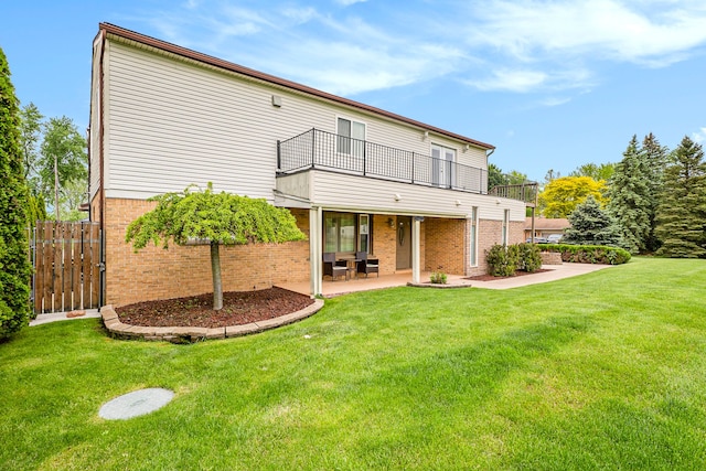 rear view of house with brick siding, a lawn, a patio area, and fence