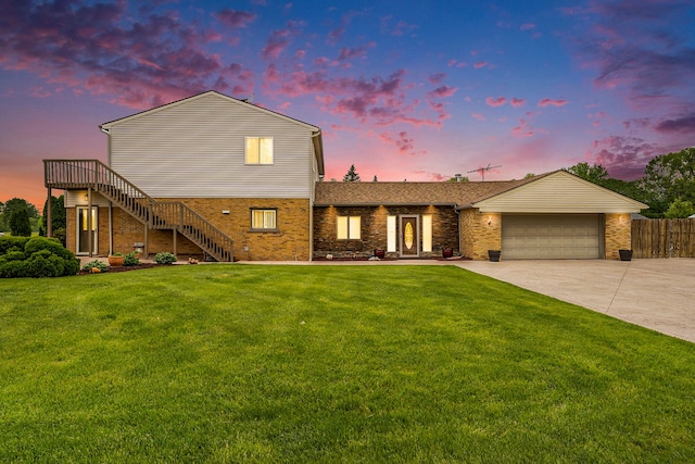 view of front of property with a garage, driveway, a lawn, stairs, and brick siding