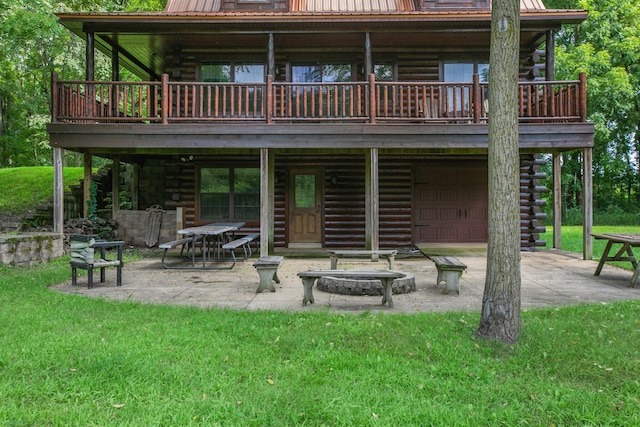 back of house with a fire pit, a lawn, log exterior, metal roof, and a patio area