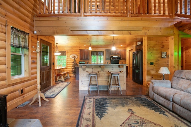 living area featuring a high ceiling, dark wood-type flooring, and visible vents