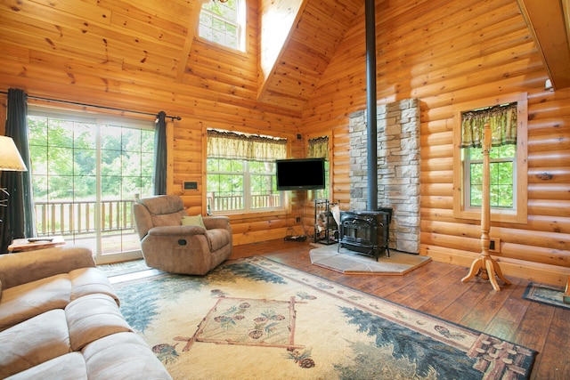 living room with high vaulted ceiling, a wood stove, rustic walls, and wood finished floors