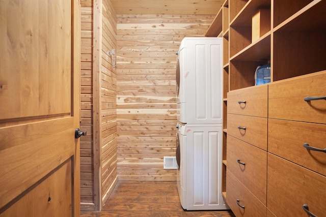 spacious closet with stacked washer / drying machine, dark wood-style flooring, and visible vents