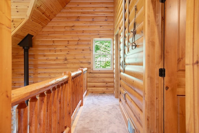 corridor with vaulted ceiling, rustic walls, visible vents, and light colored carpet