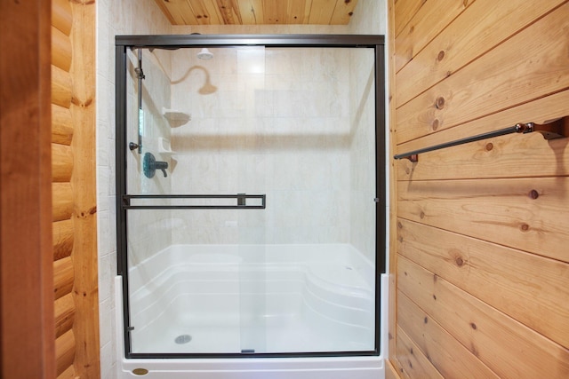 bathroom with wood walls and a stall shower