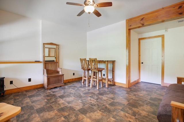 interior space featuring visible vents, a ceiling fan, baseboards, stone finish flooring, and a wood stove