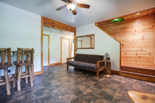 sitting room with stone finish flooring, baseboards, and a ceiling fan