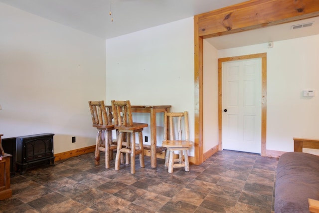 dining area with stone finish flooring, visible vents, a wood stove, and baseboards