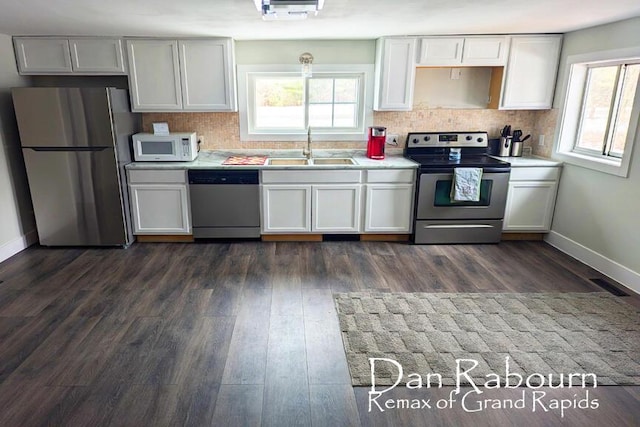 kitchen with stainless steel appliances, light countertops, a sink, and dark wood-type flooring