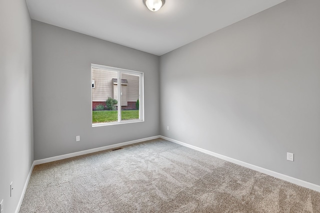 empty room featuring carpet flooring, visible vents, and baseboards