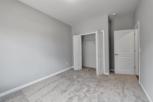 unfurnished bedroom featuring baseboards, a closet, and light colored carpet