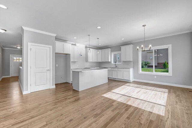 kitchen with a notable chandelier, a kitchen island, white cabinetry, light countertops, and pendant lighting