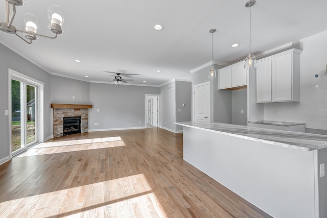 kitchen with light stone countertops, light wood finished floors, white cabinetry, and open floor plan