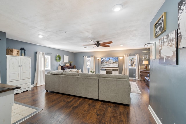 living room featuring dark wood finished floors, baseboards, and ceiling fan