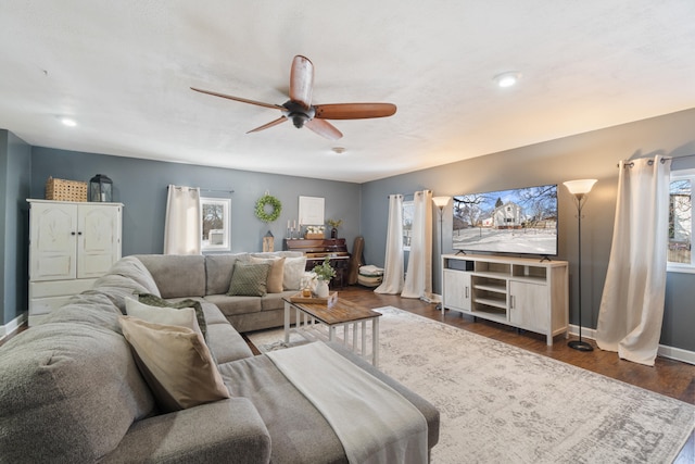 living room featuring a ceiling fan, baseboards, and dark wood-type flooring