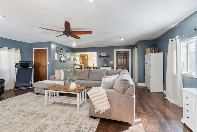 living room featuring ceiling fan, baseboards, and dark wood finished floors