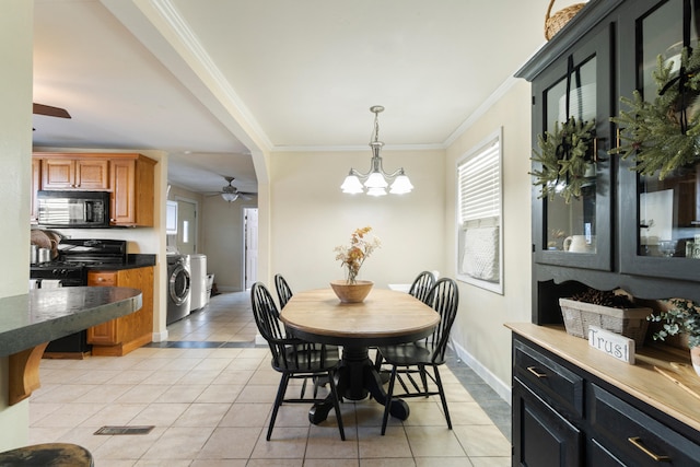 dining room with plenty of natural light, washing machine and dryer, light tile patterned flooring, and crown molding