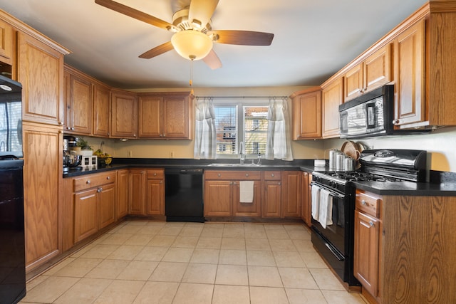 kitchen featuring dark countertops, brown cabinets, a sink, and black appliances