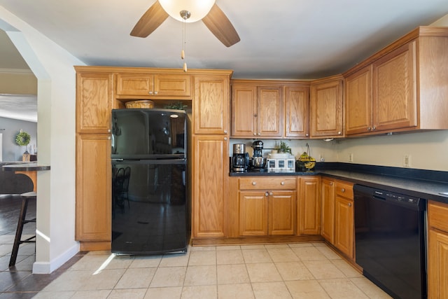 kitchen featuring light tile patterned floors, dark countertops, a ceiling fan, brown cabinetry, and black appliances