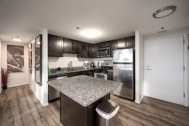 kitchen with a sink, appliances with stainless steel finishes, wood finished floors, and a center island