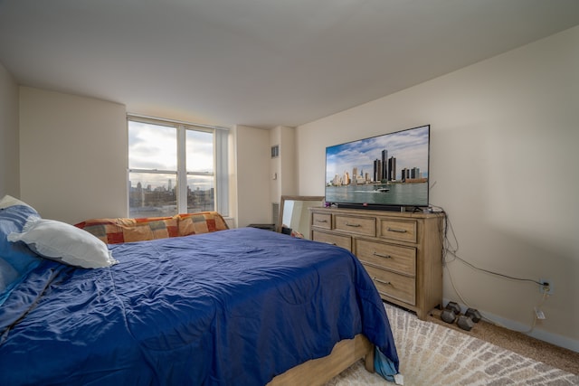 bedroom with light carpet, expansive windows, and baseboards