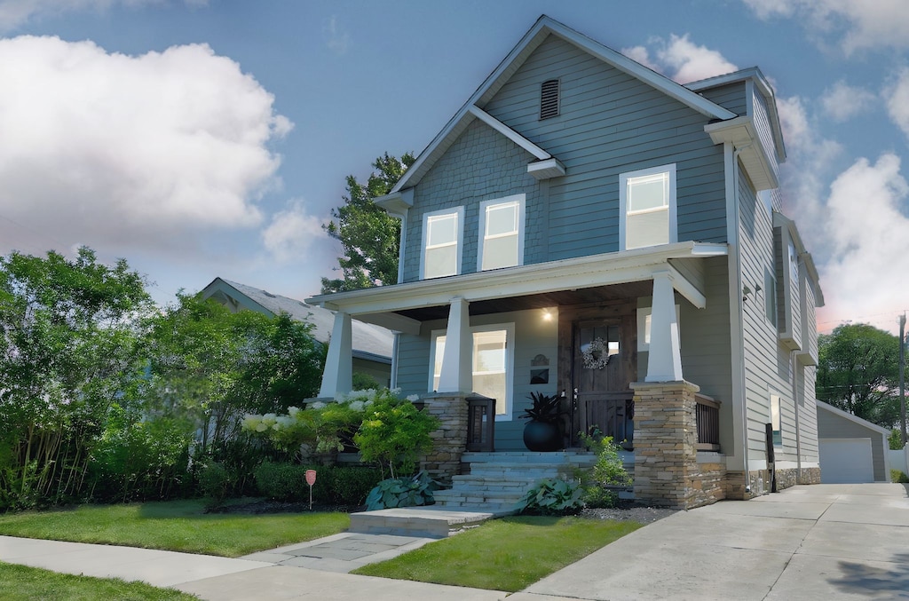 craftsman inspired home featuring covered porch, an outbuilding, a detached garage, and a front yard