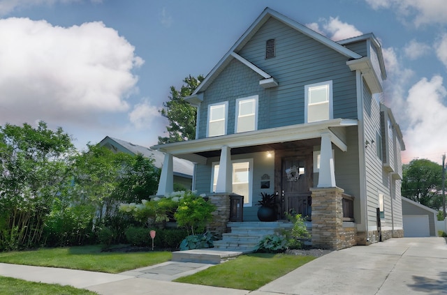 craftsman inspired home featuring covered porch, an outbuilding, a detached garage, and a front yard