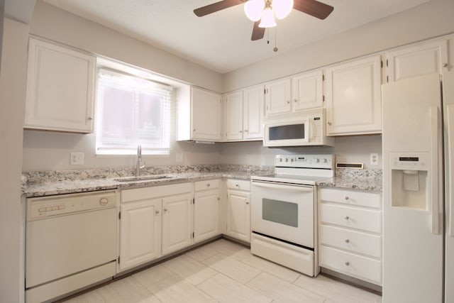 kitchen featuring white appliances, a sink, light stone counters, and white cabinetry