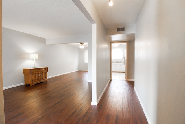 hallway featuring baseboards, visible vents, and dark wood-type flooring