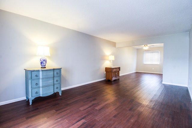 spare room with ceiling fan, baseboards, and dark wood finished floors