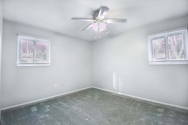 carpeted empty room with plenty of natural light, a ceiling fan, and baseboards