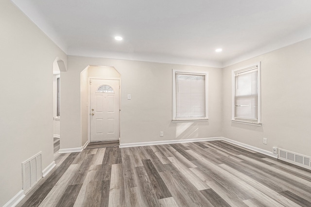 entryway featuring arched walkways, visible vents, baseboards, and wood finished floors