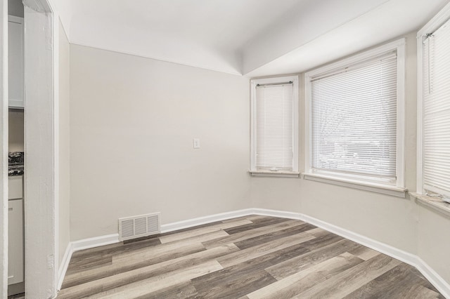 unfurnished room featuring visible vents, baseboards, and wood finished floors