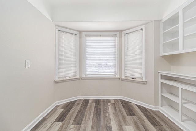 unfurnished dining area with dark wood-type flooring and baseboards