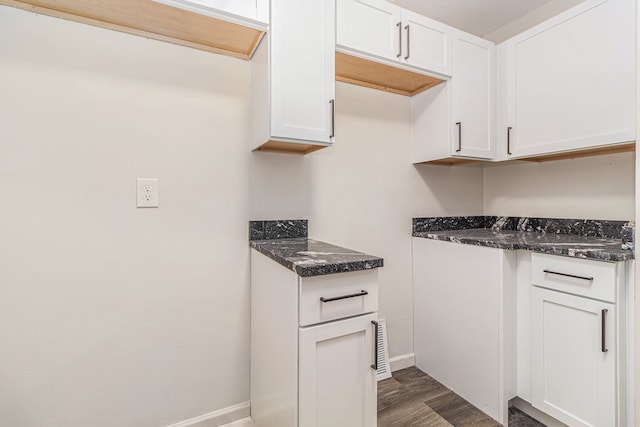 kitchen featuring baseboards, white cabinetry, dark wood-type flooring, and dark stone countertops