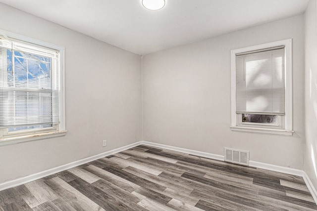 empty room featuring visible vents, baseboards, and wood finished floors