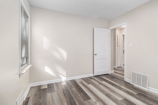 empty room featuring baseboards, visible vents, and wood finished floors