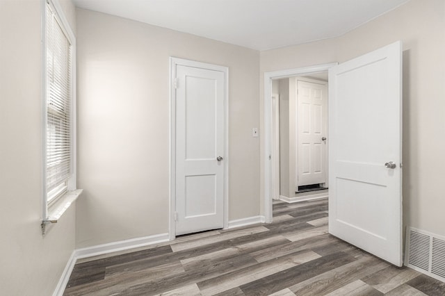 unfurnished bedroom with wood finished floors, visible vents, and baseboards