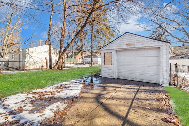 detached garage featuring concrete driveway and fence